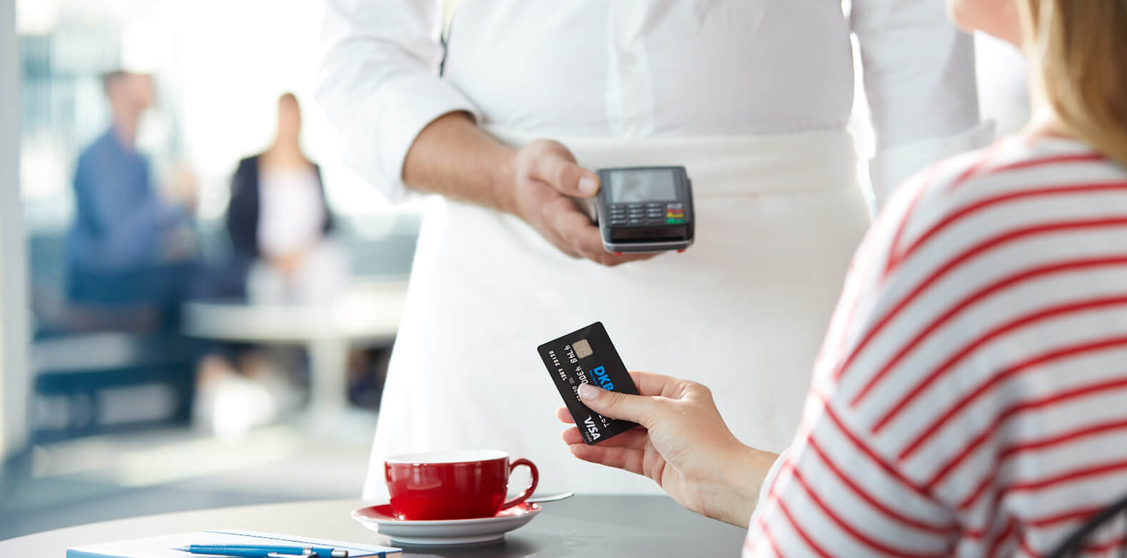 Karteninhaberin bezahlt kontaktlos mit Karte im Café